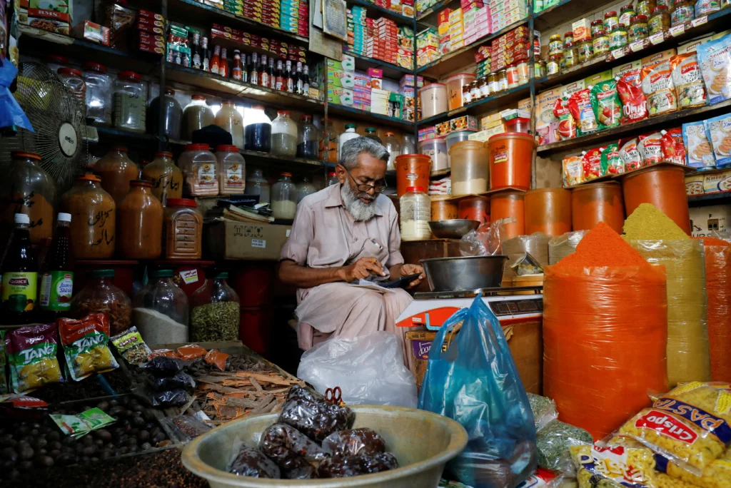 A shopkeeper using a calculator while selling spices and grocery items in a shop somewhere in Karachi, Pakistan June 11, 2021 via REUTERS/Akhtar Soomro